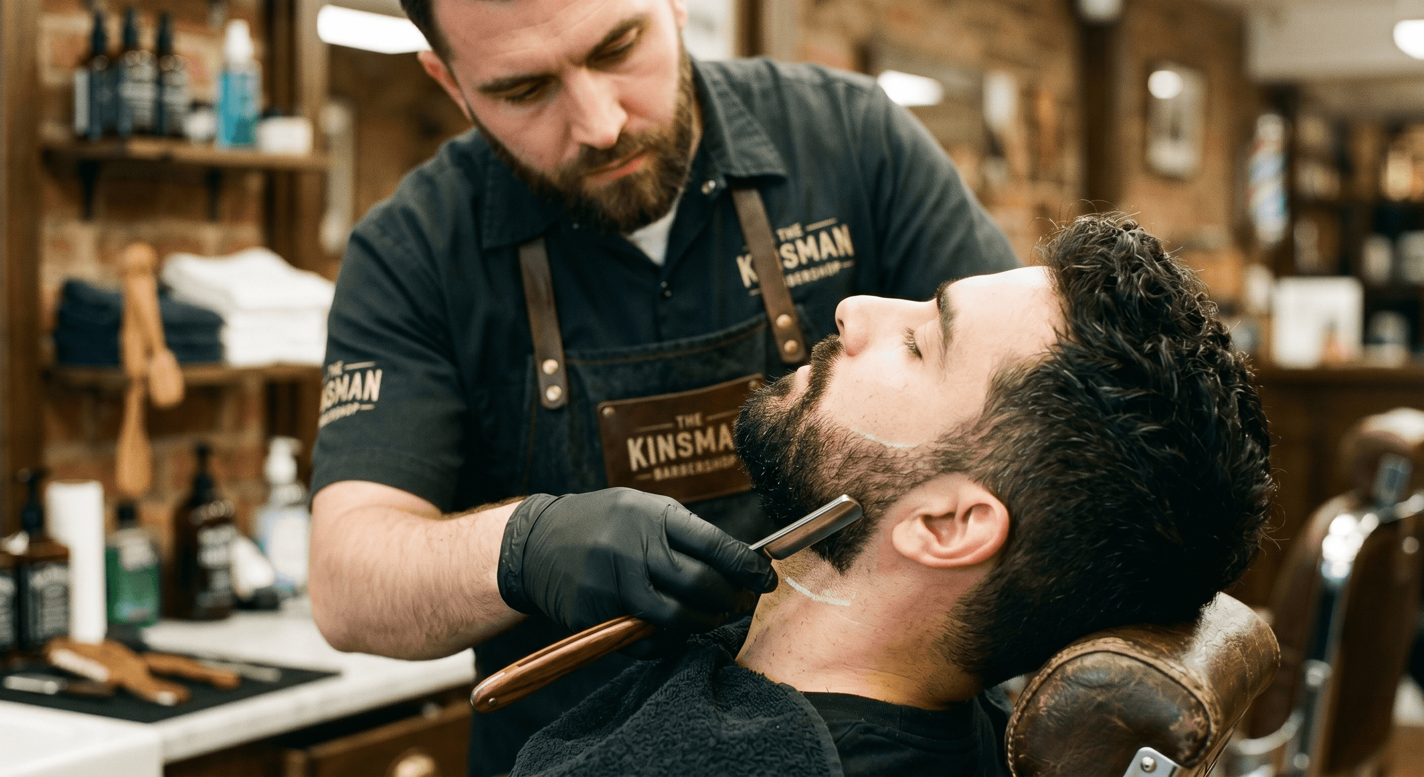 A barber shaping a client’s beard with a straight razor at The Kinsman in the West Village