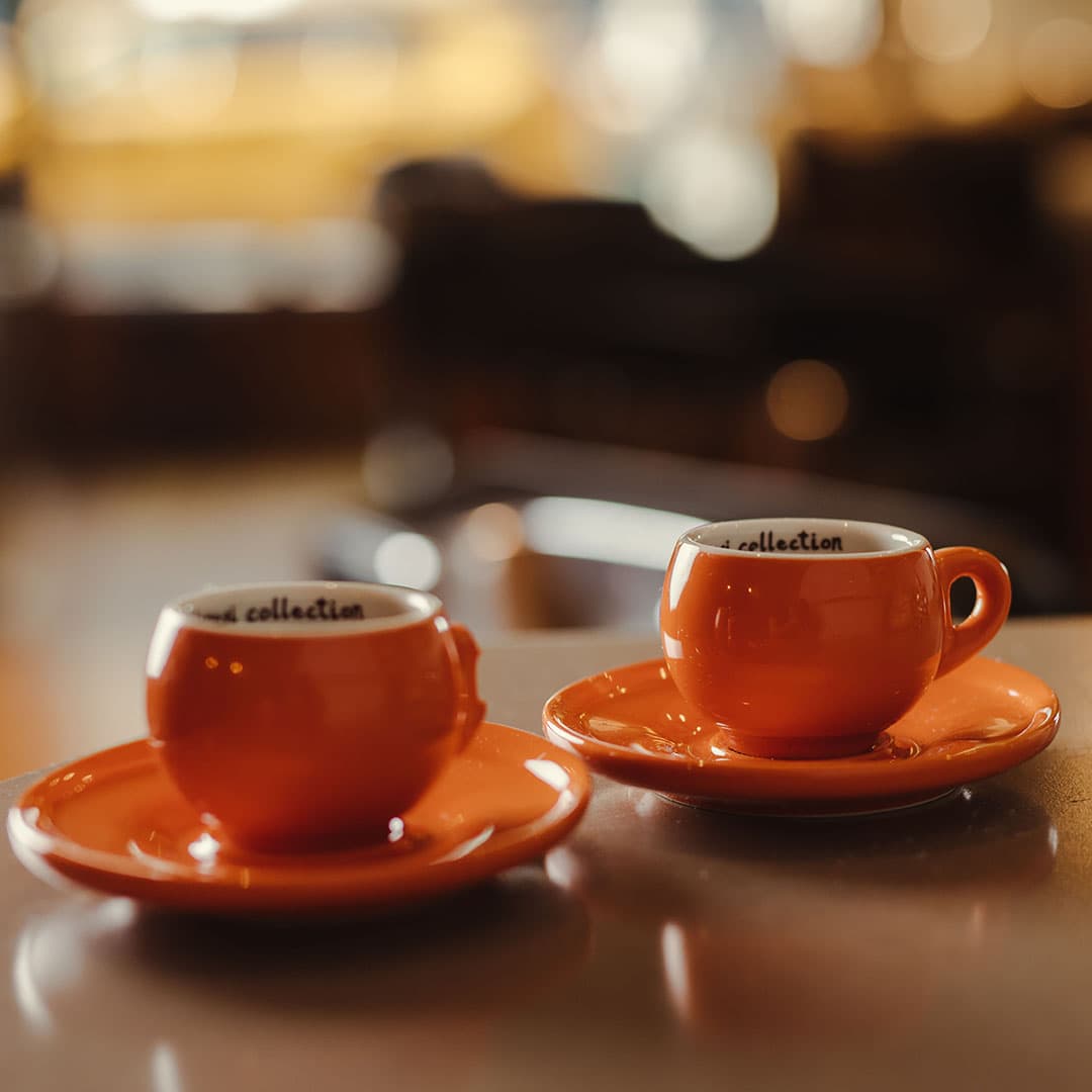 Two orange espresso cups served on a counter, highlighting the premium client hospitality and luxury experience at our West Village barbershop.