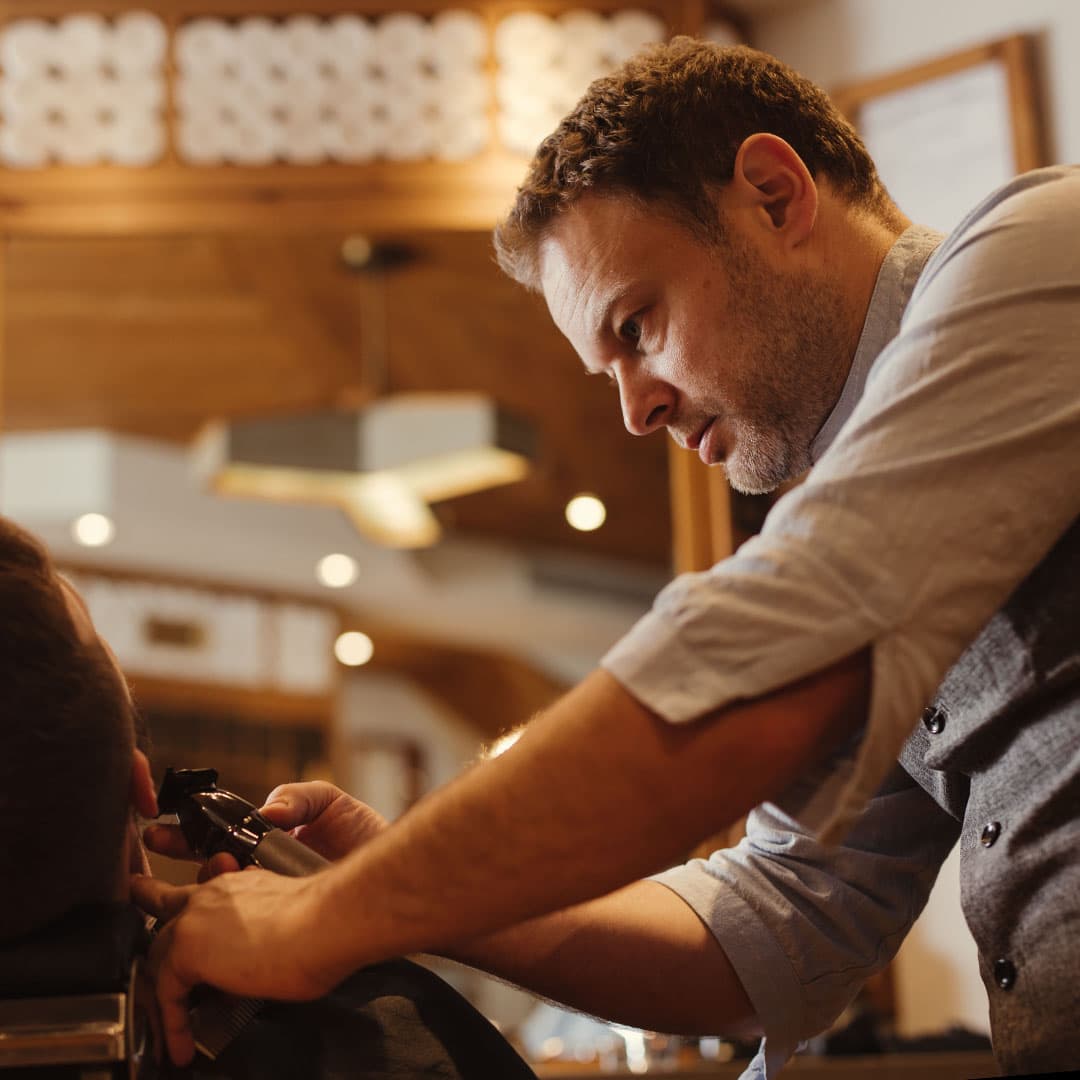 Close-up profile of a beard trim in progress at The Kinsman, showing the barber's precision using electric trimmers.