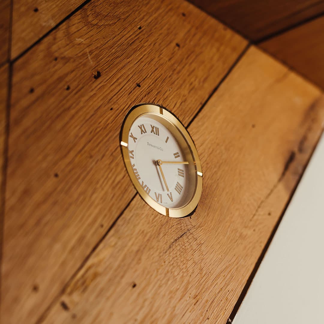 Close-up of a vintage Tiffany & Co. gold clock embedded in the reclaimed wood walls of The Kinsman barbershop in New York City.