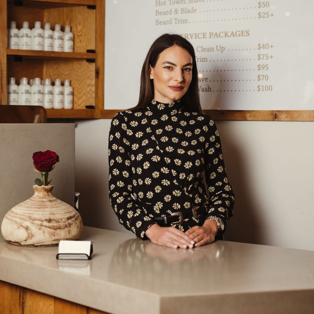 The Kinsman reception desk with a welcoming receptionist, price list, and red rose vase.
